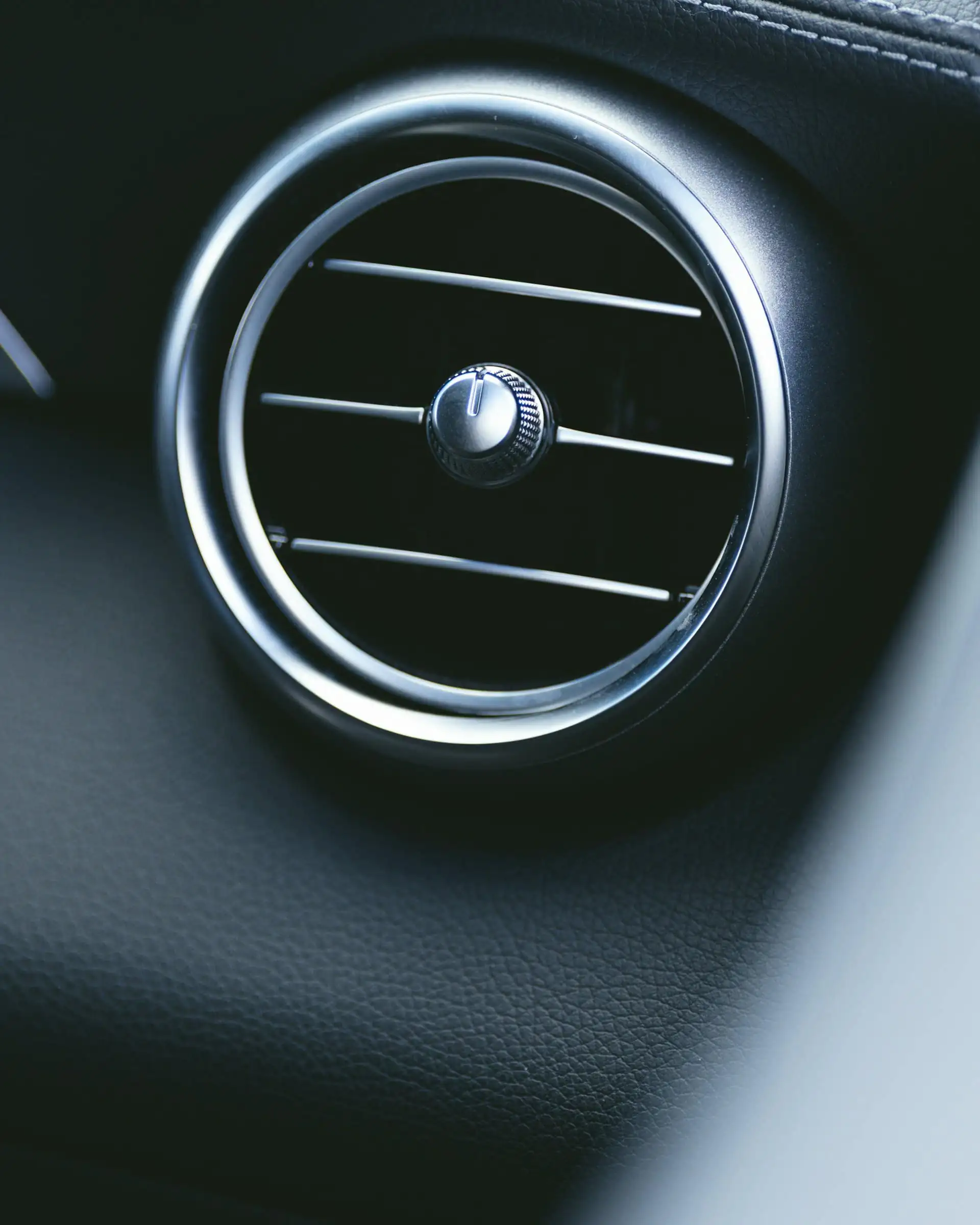 Close-up of a round air vent on a car dashboard
