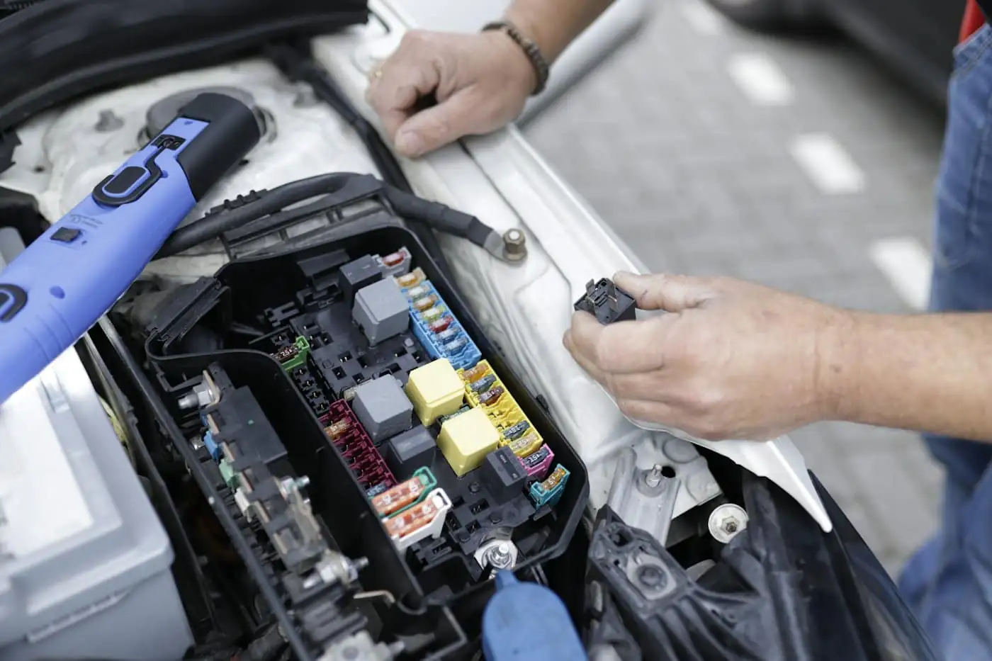 A technician testing a car's fuse box with a probe