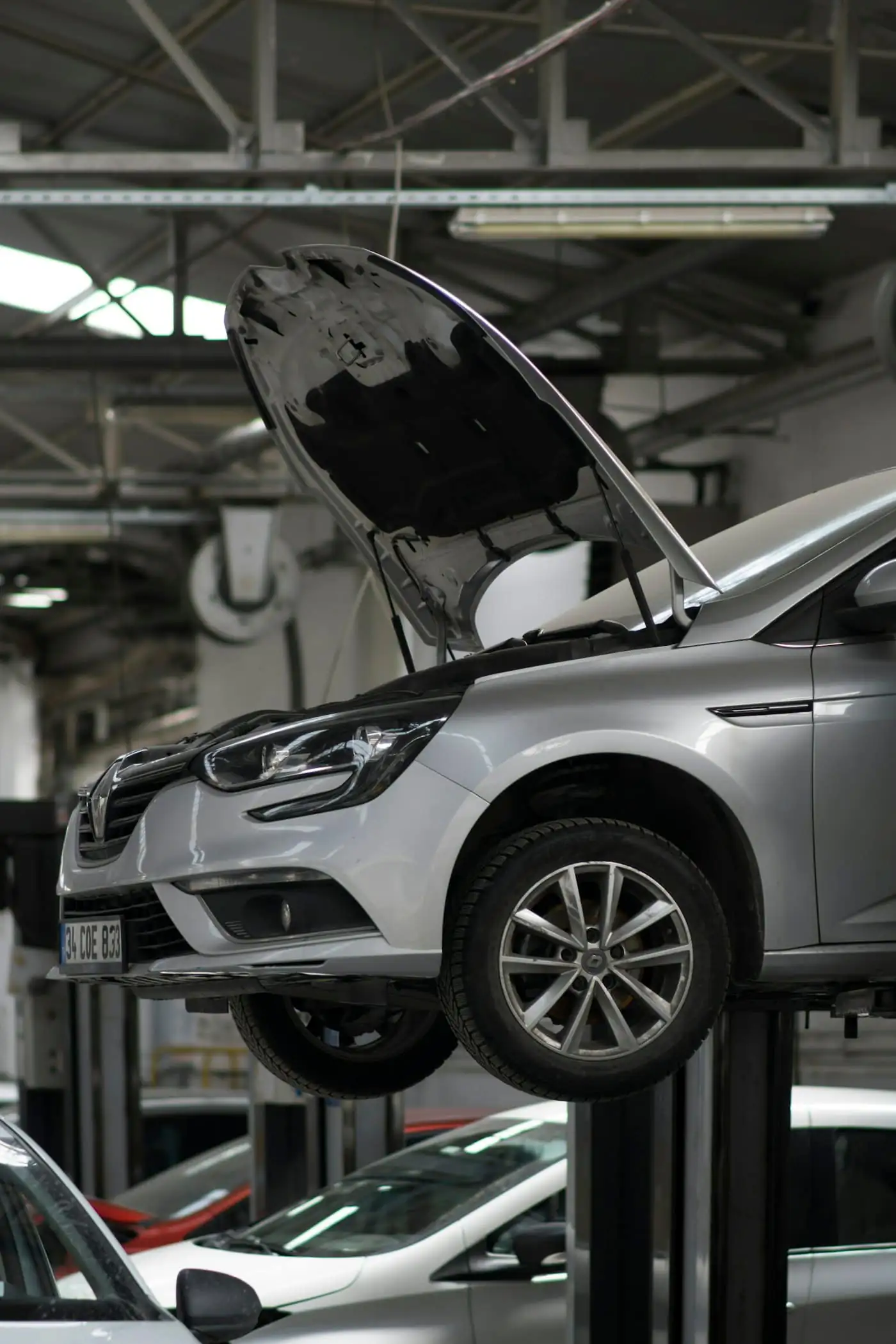 A silver car raised on a lift in a bright workshop