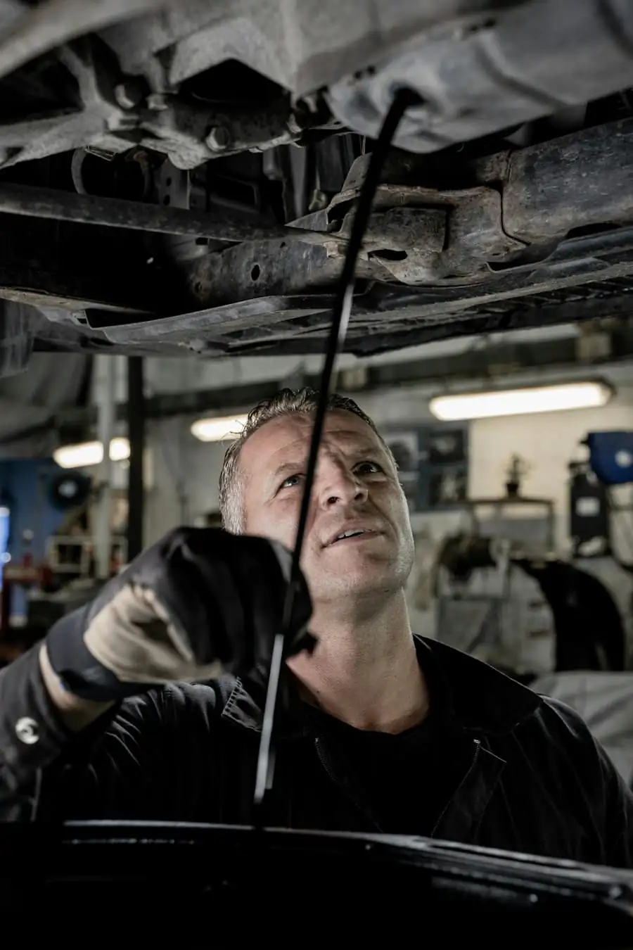 A mechanic checking the underside of the car on a lift